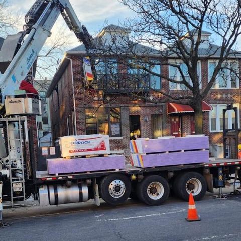 Boom truck lifting materials at a building on a city street
