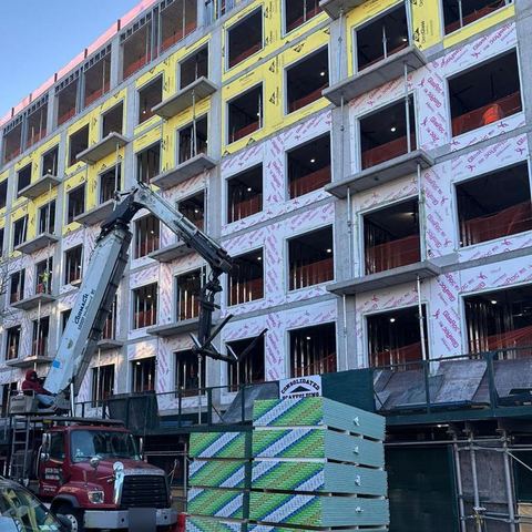 Boom crane delivering sheetrock to a building under construction